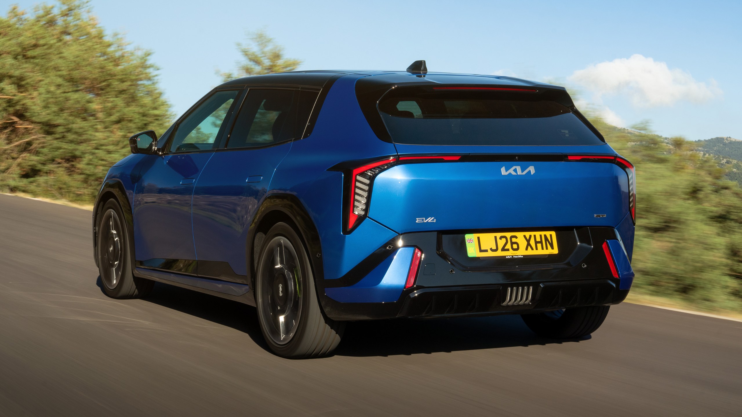 Kia EV4 GT’nin yolda hareket hâlindeki arka ve yan görünümü
