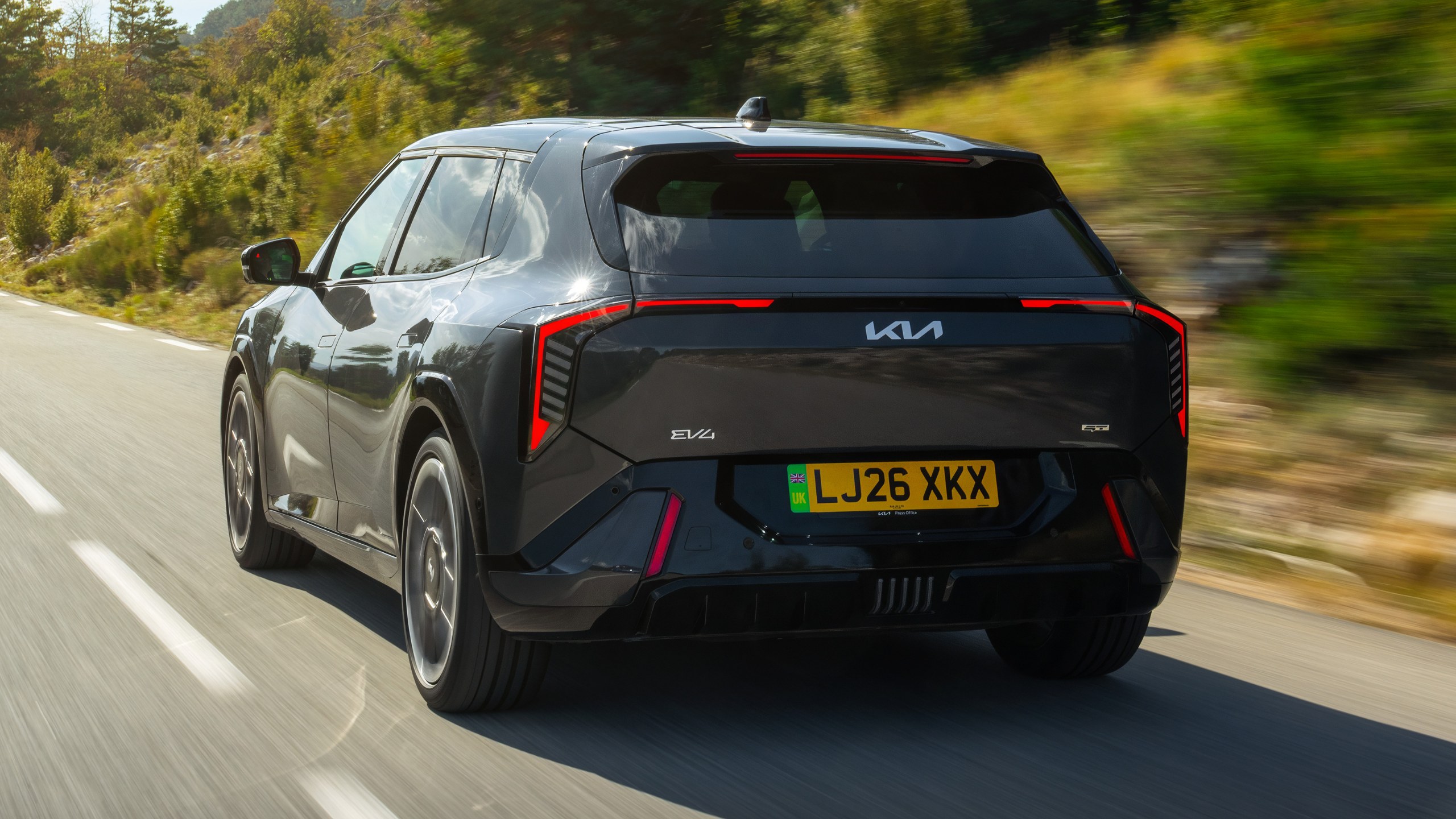 Kia EV4 GT’nin yolda ilerlerken arka görünümü